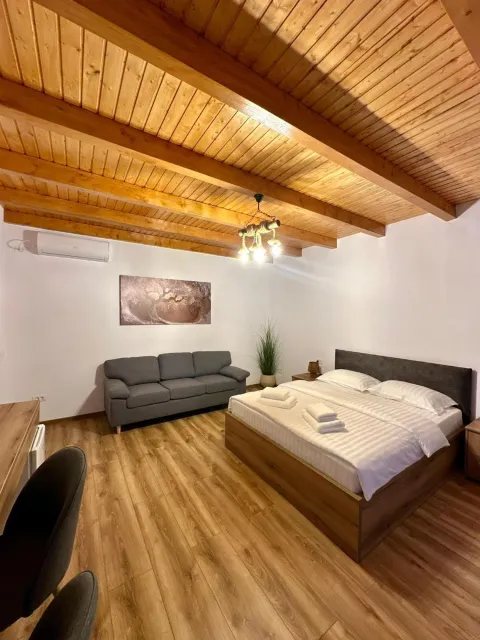 Triple room with a double bed, a sofa and a beamed wooden ceiling