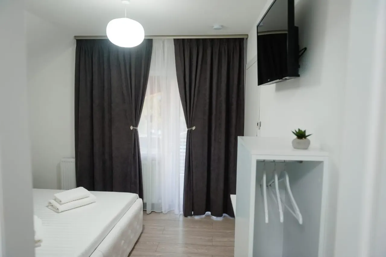 Cameră cu draperii gri închis și ușă spre balcon