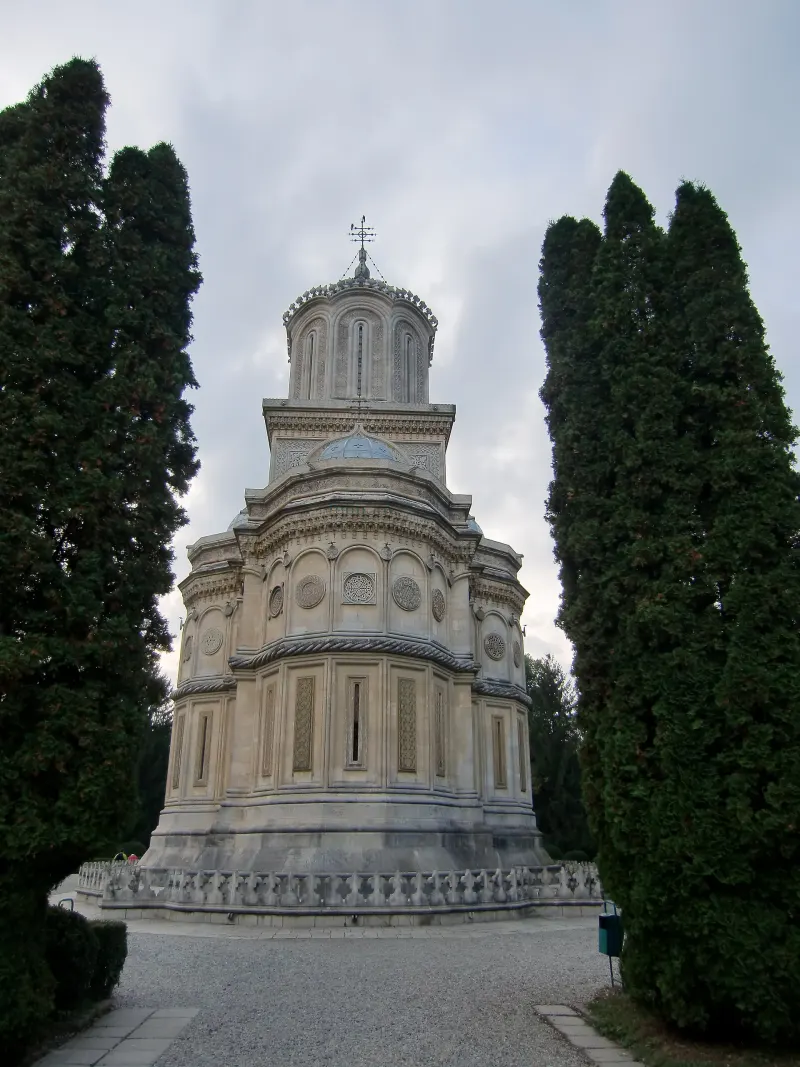 Biserica Mănăstirii Curtea de Argeș, încadrată de doi brazi înalți